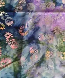 Hand-dyed tropical batik fabric featuring repeating pineapple motifs over a mesmerizing twilight blend of deep blue, purple, and green watercolor-style background.