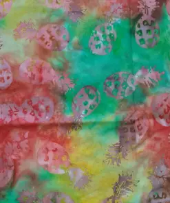 Warm tropical batik fabric in shades of red, green, and yellow featuring classic pineapple stamping.