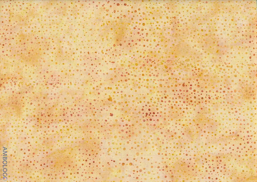 Close up of authentic orange yellow dotted batik fabric featuring a warm, sun-kissed speckled pattern on 100% premium cotton, ideal for bright sewing projects.