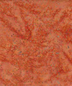 Vibrant tenne orange dotted batik fabric featuring a warm, rusty tawny hue with intricate dark blue speckles on 100% cotton, perfect for autumnal crafts.