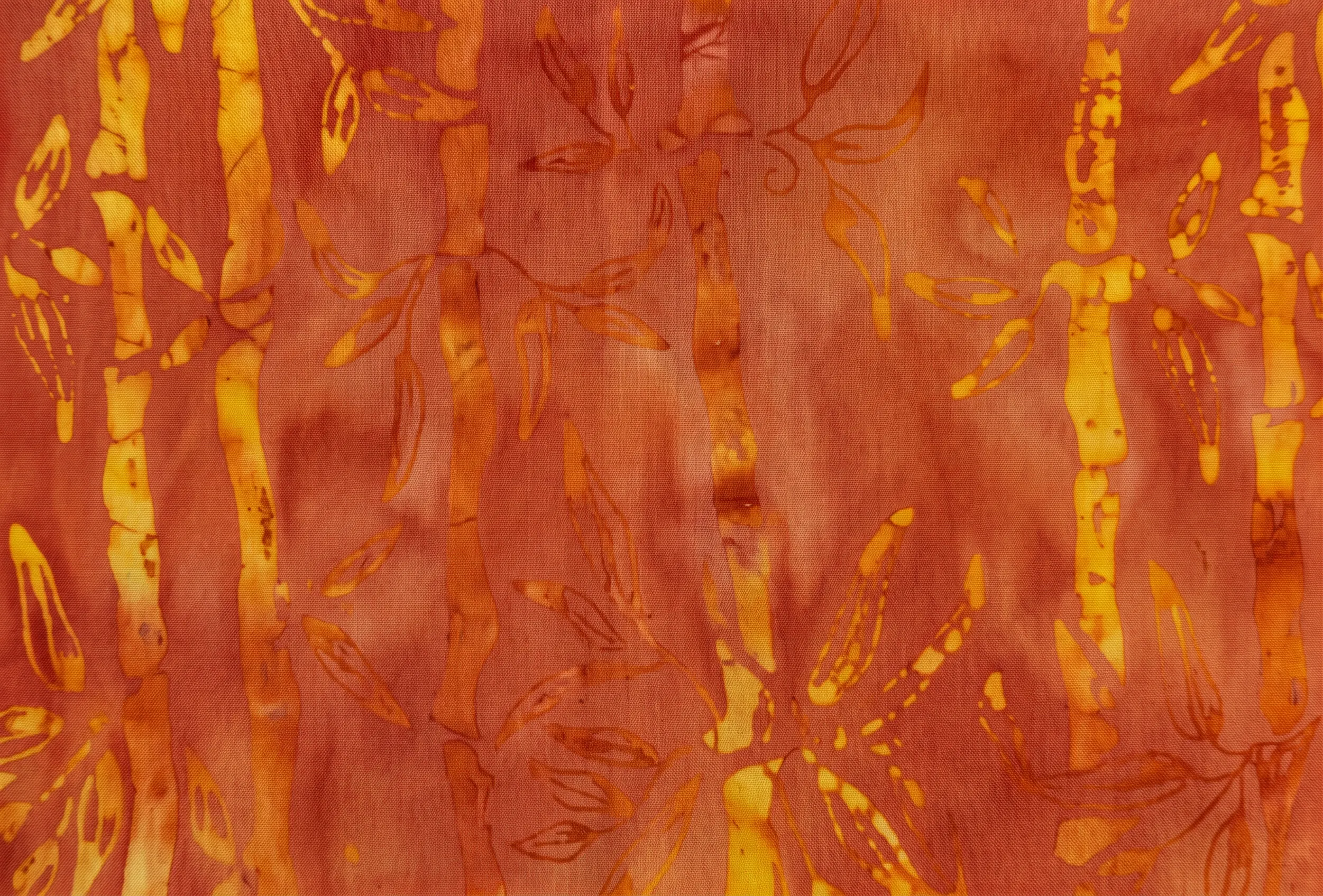 Intense burnt orange and copper batik fabric with contrasting deep indigo hues and golden bamboo prints.