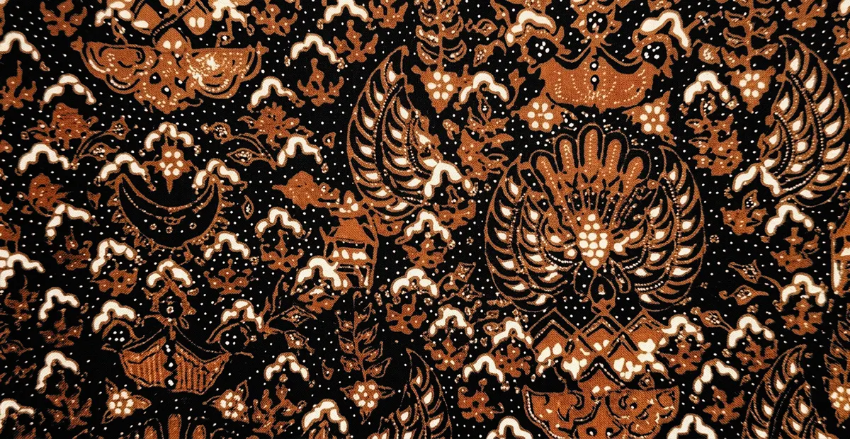 Close-up of authentic Batik Cuwiri fabric featuring Sogan brown Meru mountain and Garuda wing motifs with white cecek dots on a hand-dyed black cotton background