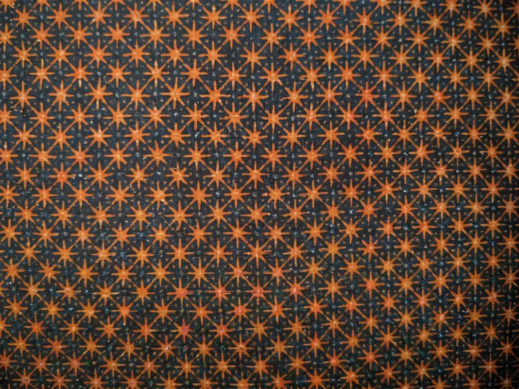Close-up of authentic Batik Truntum motif cotton fabric featuring warm sogan brown star blossoms on a true deep black background